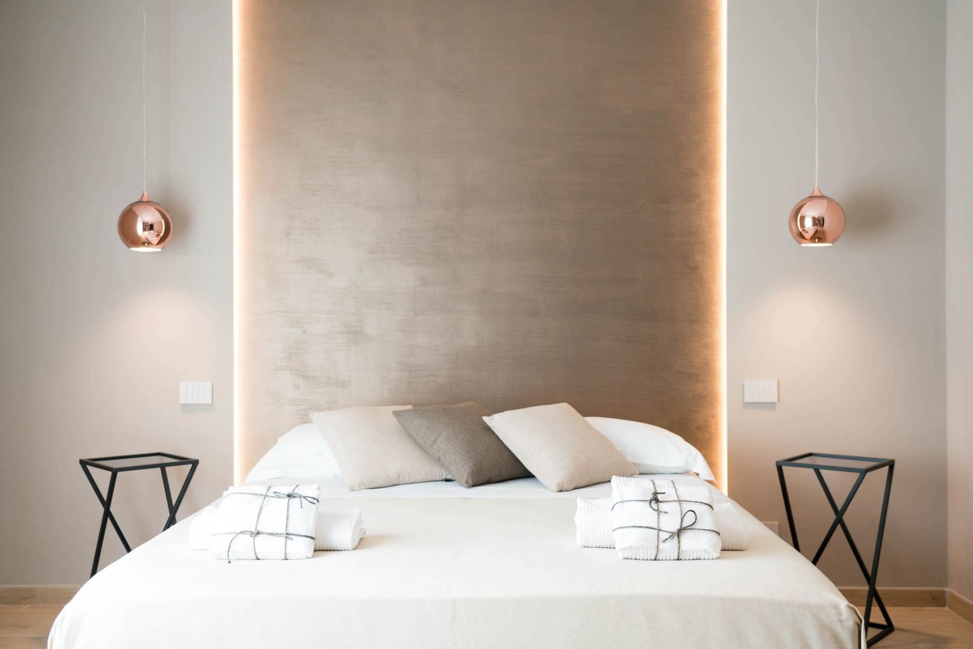 Letto matrimoniale con testata in nicchia retroilluminata e lampade a sospensione color rame